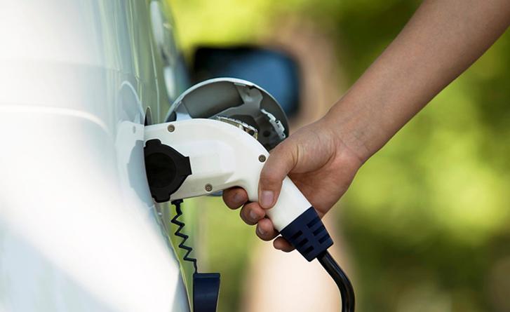 An electric car charger actively charging a white car.