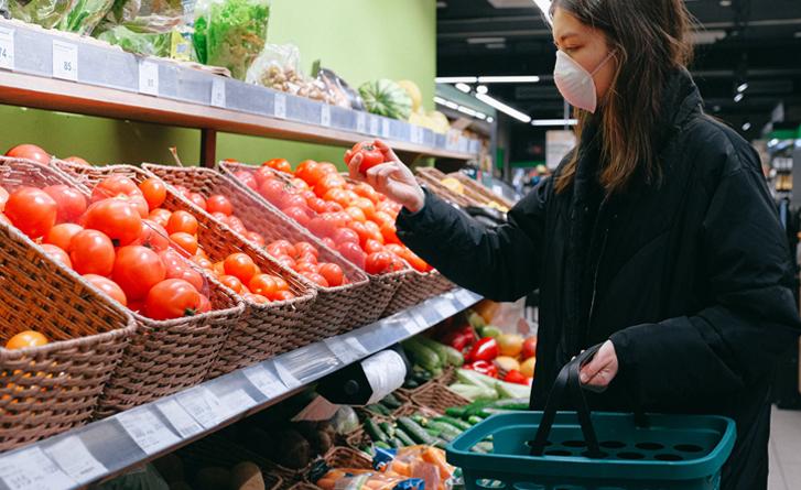 A woman shopping for fruit wearing a mask