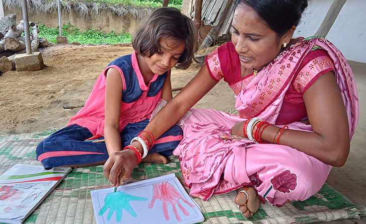 Young girl draws hand prints on paper. 