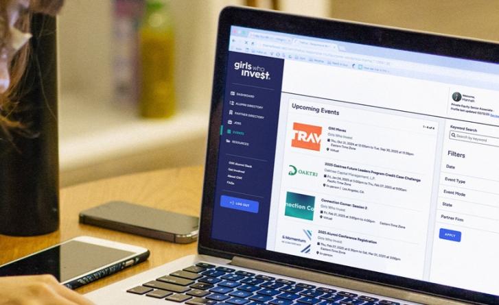 A girl looking at a laptop screen displaying the Girls Who Invest Alumni Portal dashboard. 